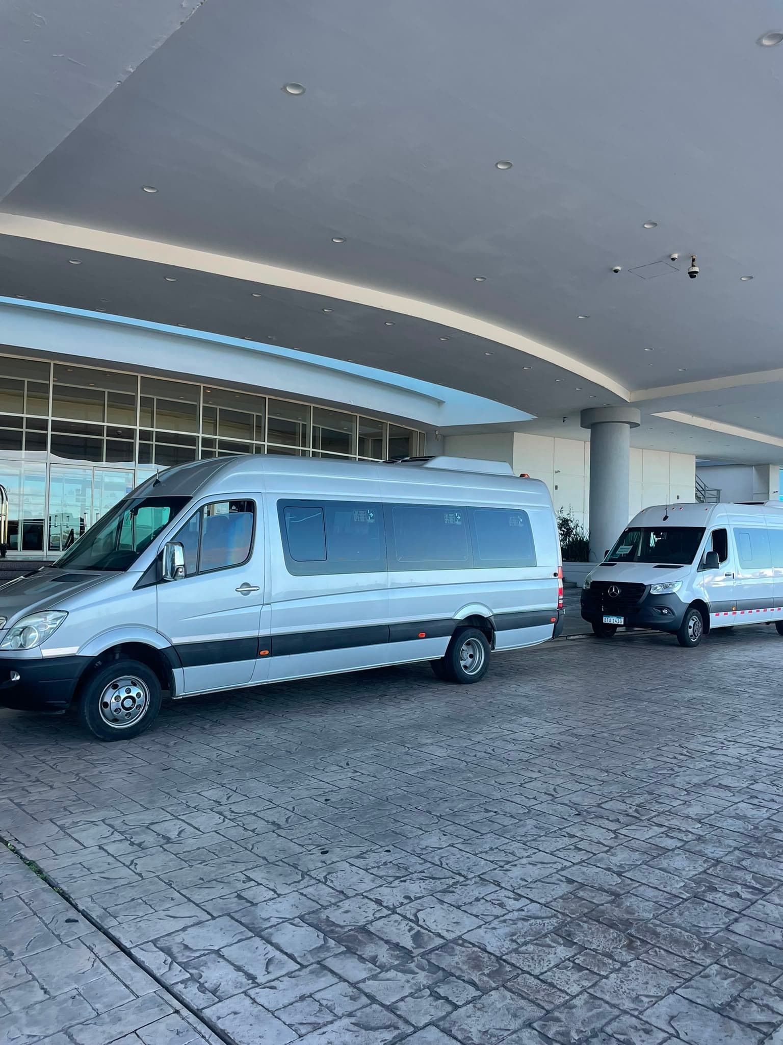 Minibús de Tino Viajes esperando en la entrada de un hotel sobre la costa